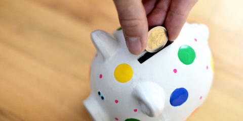 Hand steckt Geld in Sparschwein