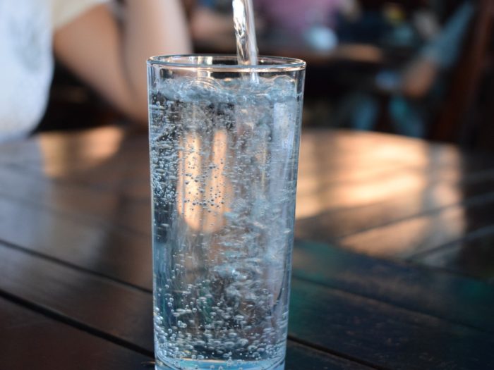 Mineralwasser wird in ein Glas eingegossen.